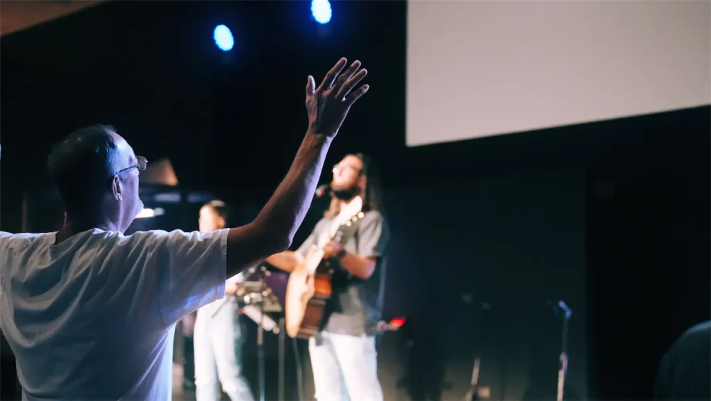 man worshiping with arms raised.