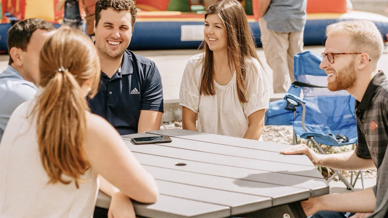 Young adults sitting around a picnic table